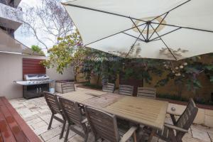 a wooden table and chairs with an umbrella on a patio at Boutique Stays - Elwood Hideaway in Melbourne