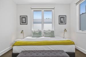 a white bedroom with a large bed with two windows at Boutique Stays - Victorian Vogue in Melbourne