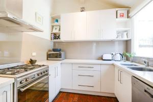 a white kitchen with white cabinets and a sink at Boutique Stays - Clifton Park in Melbourne