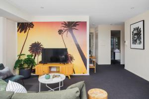 sala de estar con TV y palmeras en la pared en Boutique Stays - Zinc Views 501, en Melbourne