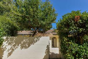 a white fence in front of a house with trees at Brighton Rose in Melbourne