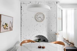 a white dining room with a table and a clock at Boutique Stays - The Vault in Melbourne