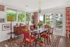 a dining room with a table and chairs and windows at Boutique Stays - That 70s House in Mount Waverley