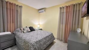 a bedroom with a bed and a dresser and a television at Home close to the beach, free wifi & parking, in quiet neighborhood equipped with ACs in Nagua