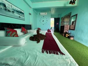 a bedroom with a large white bed with a red dress on it at ไร่ชาชิวอวี๋ in Pai