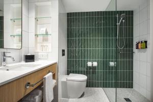 a bathroom with a shower and a toilet and a sink at Holiday Inn Dandenong, an IHG Hotel in Dandenong