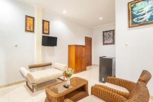 a living room with chairs and a couch and a tv at Nirmala Guest House Surf Keramas in Keramas