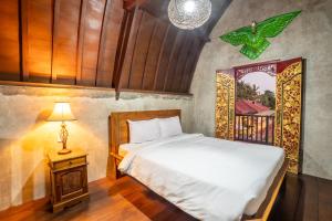 a bedroom with a bed and a lamp and a window at Nirmala Guest House Surf Keramas in Keramas