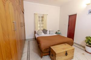 een kleine slaapkamer met een bed en een houten deur bij Cozy 4BHK Villa in Bangalore