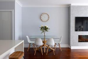 Un comedor con una mesa y sillas y un reloj. en Boutique Stays - Two Plus Two, en Melbourne