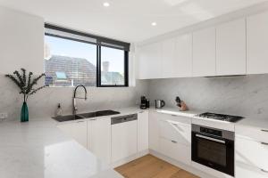een witte keuken met witte kasten en een raam bij Boutique Stays - Elmtree in Melbourne