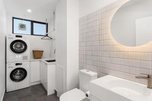 een witte badkamer met een wasmachine en een wastafel bij Boutique Stays - Elmtree in Melbourne +12 foto's