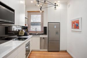 a kitchen with a stainless steel refrigerator and white cabinets at Boutique Stays - Cherrybombe in Melbourne