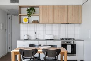 メルボルンにあるBoutique Stays - Axel Apartments 202 The Radnorのキッチン(木製テーブル、椅子付)