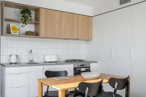 メルボルンにあるBoutique Stays - Axel Apartments 202 The Radnorのキッチン(木製テーブル、いくつかの椅子付)