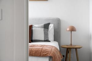 メルボルンにあるBoutique Stays - Axel Apartments 202 The Radnorのベッドルーム1室(ベッド1台、テーブルの上にランプ付)