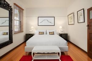 a bedroom with a white bed and a mirror at Boutique Stays - Cherrybombe in Melbourne