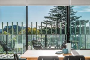 una oficina con mesa, sillas y ventanas grandes en Boutique Stays - Axel Apartments 203 The Bonfield en Melbourne