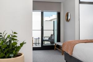 メルボルンにあるBoutique Stays - Axel Apartments 203 The Bonfieldのベッドルーム1室(ベッド1台付)が備わります。バルコニーの景色を望めます。