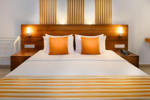 a bedroom with a large bed with orange pillows at Camelot Beach Hotel in Negombo