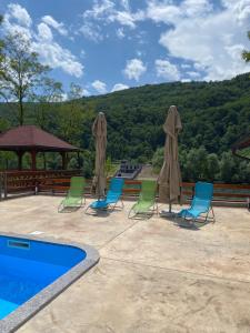 a group of chairs and umbrellas next to a swimming pool at Mini Deluxe Apartman Nature Connection Drina in Bajina Bašta