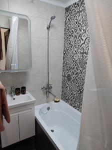 y baño con bañera y cortina de ducha. en Квартира en Karagandá