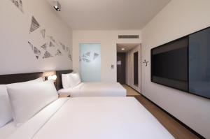 Habitación de hotel con cama blanca grande y TV de pantalla plana. en Aloft Singapore Novena en Singapur
