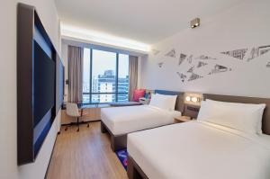 ein Hotelzimmer mit 2 Betten und einem Flachbild-TV in der Unterkunft Aloft Singapore Novena in Singapur