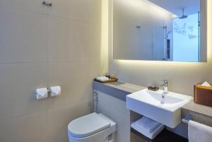 a bathroom with a sink and a toilet and a mirror at Aloft Singapore Novena in Singapore