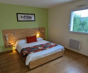 a bedroom with a bed with a red pillow and a window at Le Libenter in Landéda