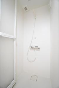 y baño blanco con ducha y cabezal de ducha. en MATATABI STAY Alita Motomachi 3F, en Osaka