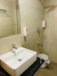 a bathroom with a white sink and a toilet at Hotel Emora Tree in Mysore
