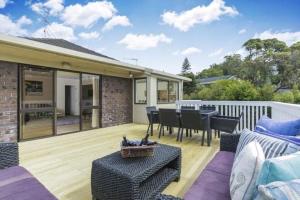 un patio con mesa y sillas en una terraza en Scherff Road Holiday Home en Auckland