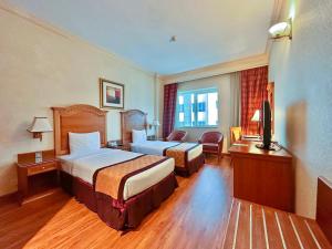 Habitación de hotel con 2 camas y TV en Avenue Hotel Dubai, en Dubái