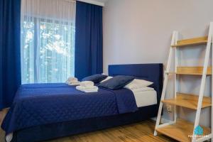 ein Schlafzimmer mit einem blauen Bett und einem Fenster in der Unterkunft Pod Brzozami Apartamenty Villa Solny in Ustronie Morskie