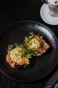 a black plate with two eggs on top of food at Žilvinas Hotel in Palanga