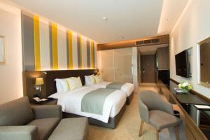 um quarto de hotel com uma cama, uma secretária e cadeiras em Lancaster Bangkok em Bangkok