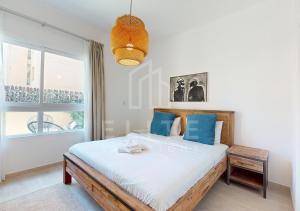 a bedroom with a bed with blue pillows and a window at Fully Furnished 1BR Apartment with Stunning Interior in Dubai