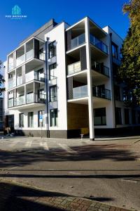 ein weißes Mehrfamilienhaus am Straßenrand in der Unterkunft Pod Brzozami Apartamenty Villa Solny in Ustronie Morskie