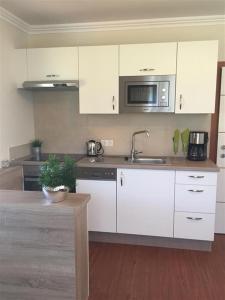 a kitchen with white cabinets and a microwave at Appartement Mühlbacher in Wagrain