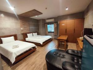 a hotel room with two beds and a couch at Komol Residence Bangkok in Bangkok