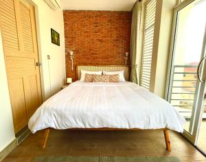 Bett in einem Zimmer mit Ziegelwand in der Unterkunft Cambodhi - Vegan Guesthouse in Kampot