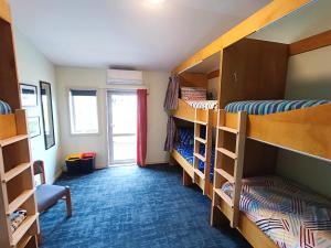 a room with three bunk beds and a window at Adventure Wanaka Hostel in Wanaka