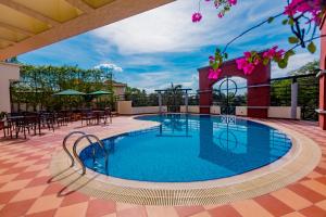 a pool on the roof of a building with tables and chairs at Hotel Grand Park Barishal in Barisāl