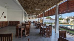 a restaurant with wooden tables and chairs and a pool at Mafia Dream Hotel in Kilindoni