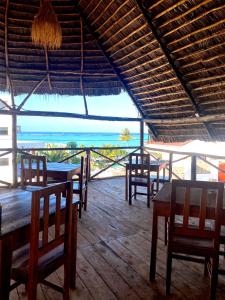 a restaurant with tables and chairs and a view of the ocean at Kokopelli Bungalows in Nungwi