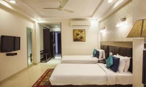 two beds in a hotel room with a tv at FabHotel Prime Hema's Supreme in Visakhapatnam