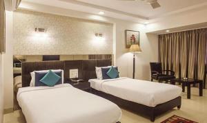 a hotel room with two beds and a desk at FabHotel Prime Hema's Supreme in Visakhapatnam