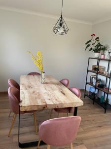 a dining room with a wooden table and pink chairs at Appartement F3 Cocooning in Montigny-lès-Metz