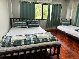 a bedroom with two beds with green curtains at Chill @ Phetchaburi in Phetchaburi